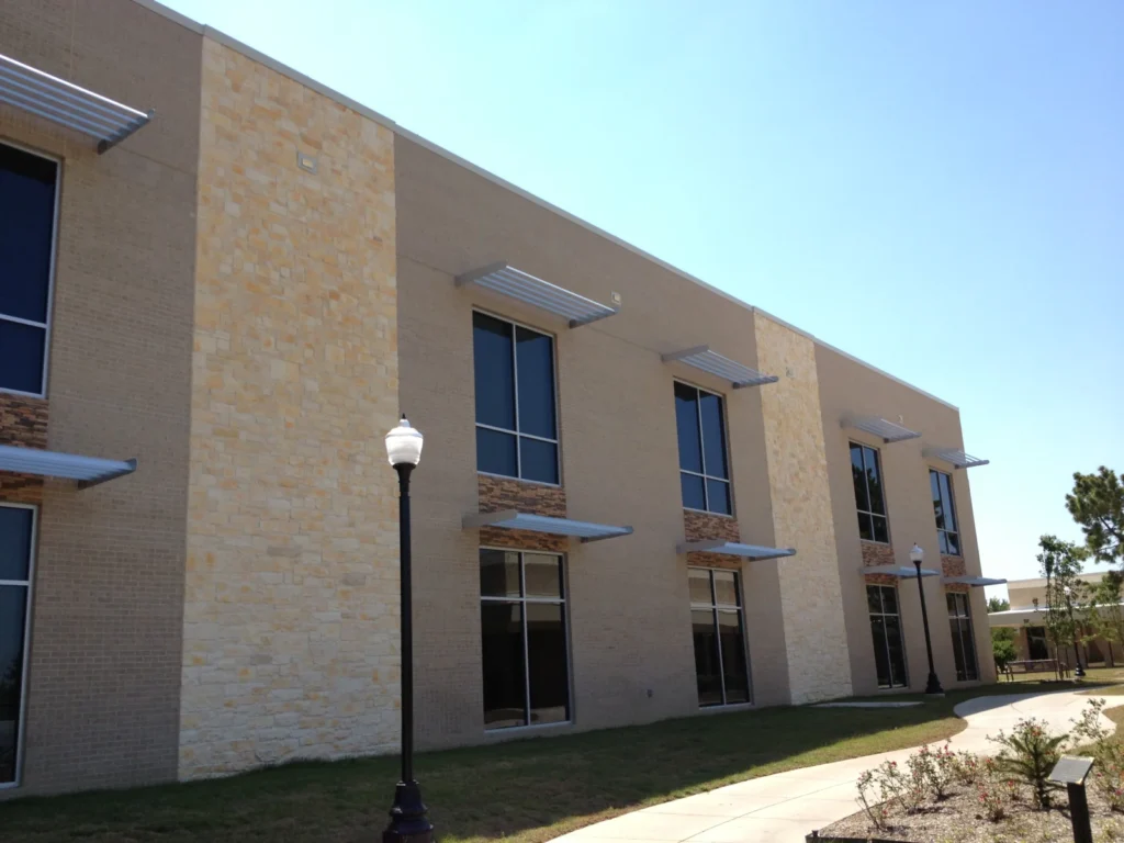 Aluminum sunshades over the windows of a two-story stone office building