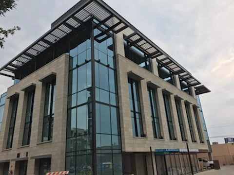 Black aluminum rooftop trellis on a four-story stone and glass office building
