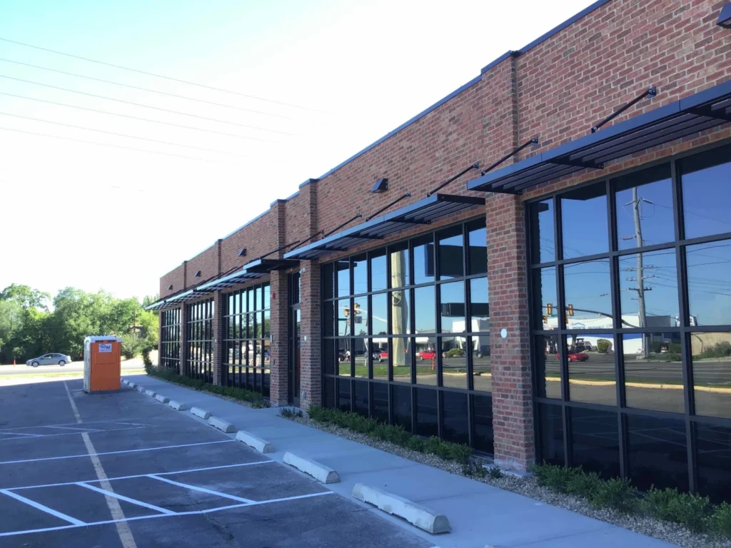 Dark aluminum sunshades along the storefront windows of a brick retail building